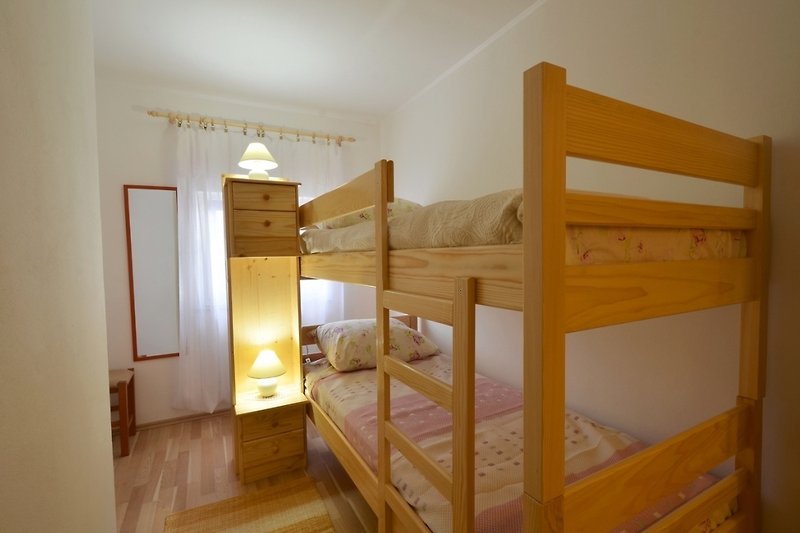 Comfortable bedroom with bunk bed, wooden furniture, and cozy lighting.