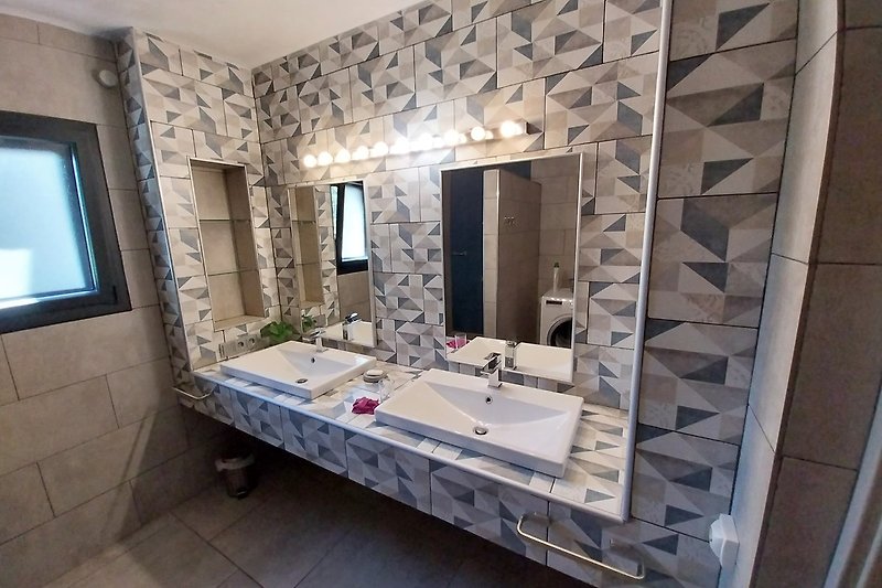 Badezimmer mit Spiegel, Fliesen und Badewanne.