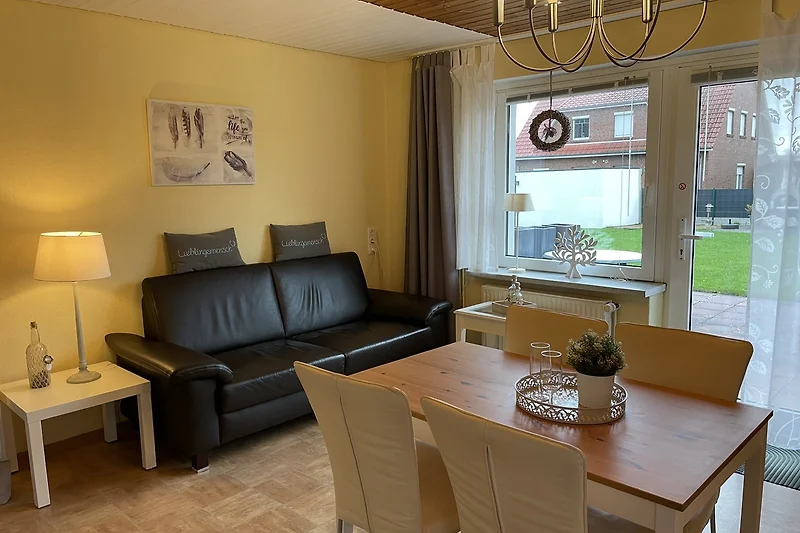 Heller Wohnraum mit Sofa , Essplatz und Blick auf die Terrasse