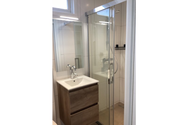 Modernes Badezimmer mit Glasdusche, Holzwaschtisch, Spiegel und WC.