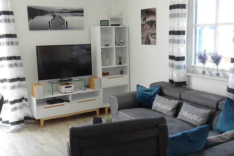 Gemütliches Wohnzimmer mit grauem Sofa und Sessel.