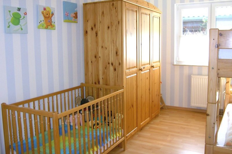 Kinderzimmer mit Etagenbett sowie Kinderbett und Hochstuhl