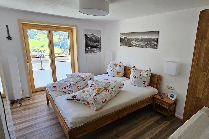 Gemütliches Schlafzimmer mit Holzbett, Fenster und stilvoller Beleuchtung.