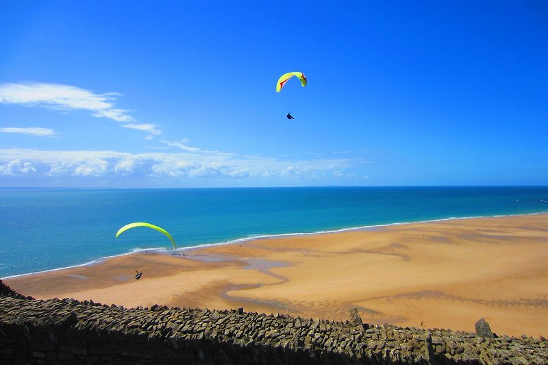 Paragliding über karibischem Strand mit azurblauem Meer. Abenteuer in der Luft!  JERSEY Insel am links