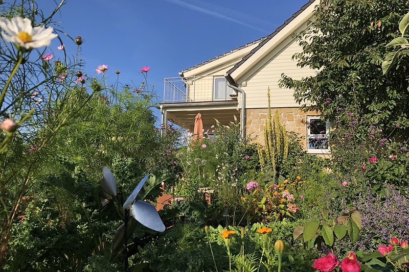 Blühender Garten mit Bäumen und Sträuchern vor dem Haus.