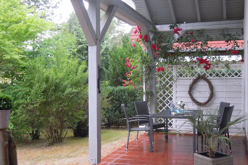 Überdachte Terrasse mit Gartenblick, Pavillon und stilvollem Outdoor-Tisch.