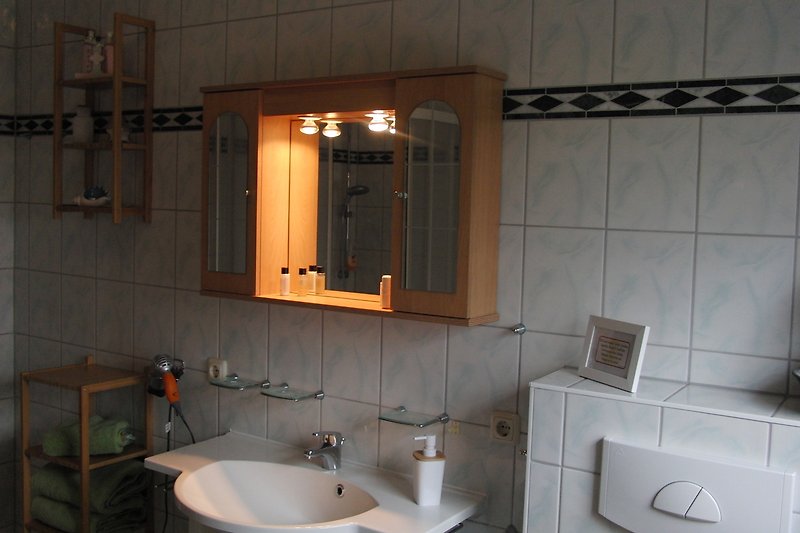 Badezimmer im EG mit Spiegel, Waschbecken und Schrank.
