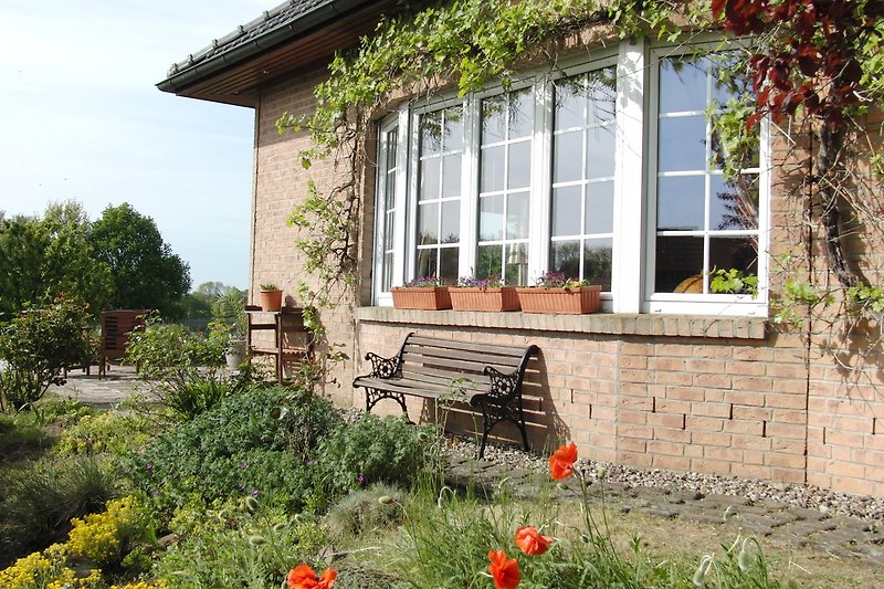 Ein idyllisches Haus mit blühendem Garten und gemütlichem Sitzplatz.