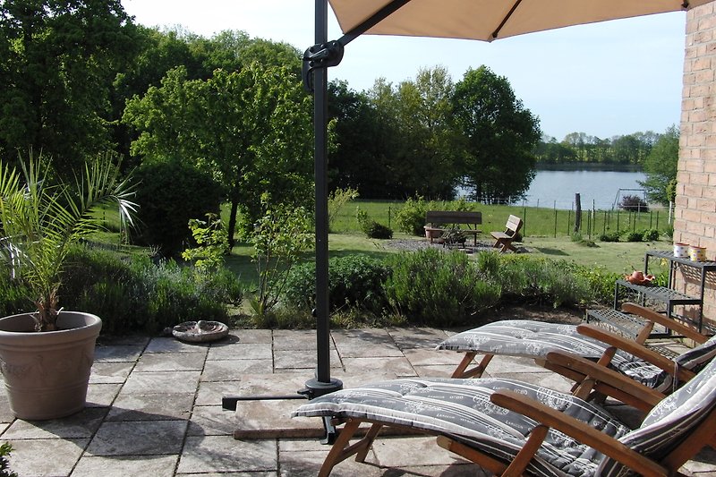 Schöner Garten mit Pflanzen, Sonnenschirm und Outdoor-Möbeln.