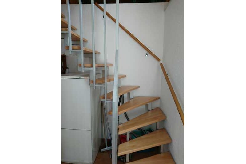 Holztreppe mit Geländer und Holzboden in einem geräumigen Raum.
