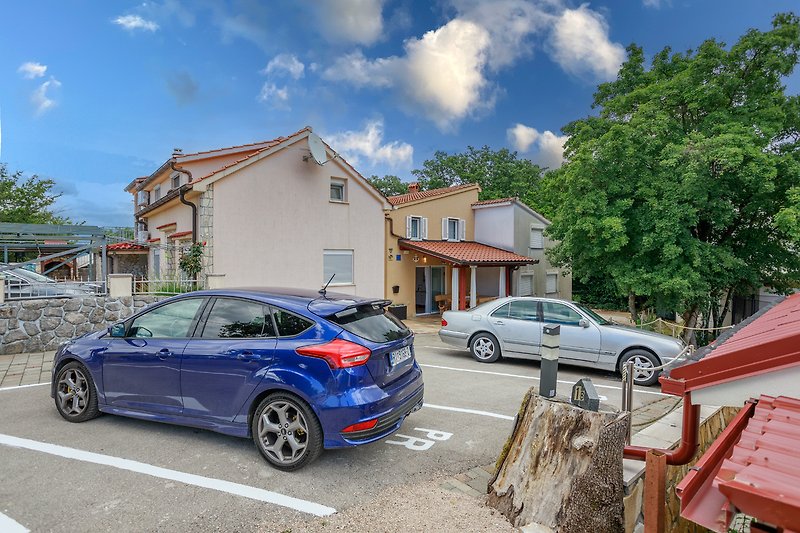 Ein Haus mit einem Auto, Rädern und einem blauen Himmel.