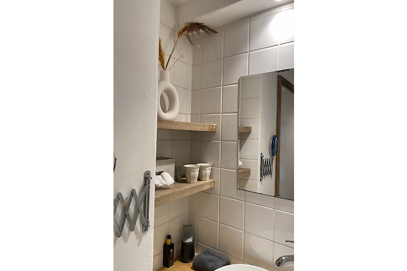 Stilvolles Badezimmer mit Holzmöbeln, Metallarmaturen und elegantem Design.