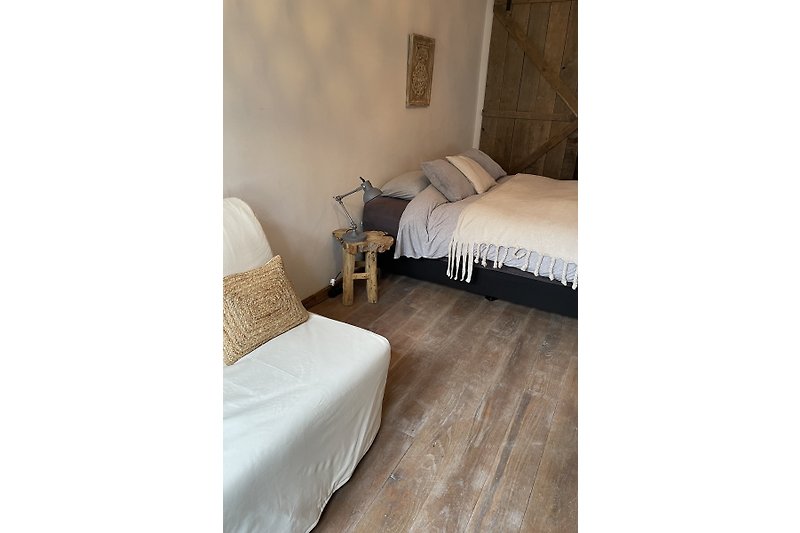 Gemütliches Zimmer mit Holzboden, bequemen Betten und stilvoller Lampe.