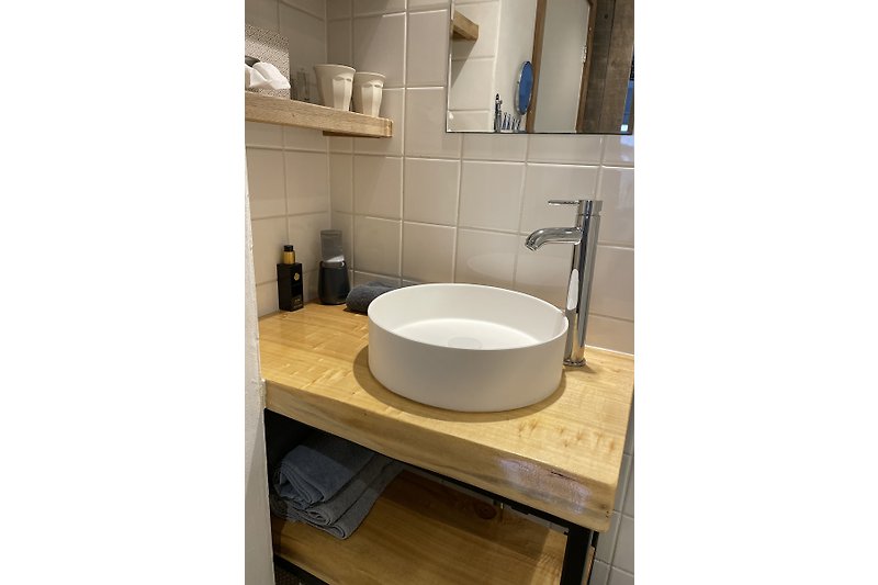 Schönes Badezimmer mit Holzwaschbecken, Keramiktoilette und Spiegel.