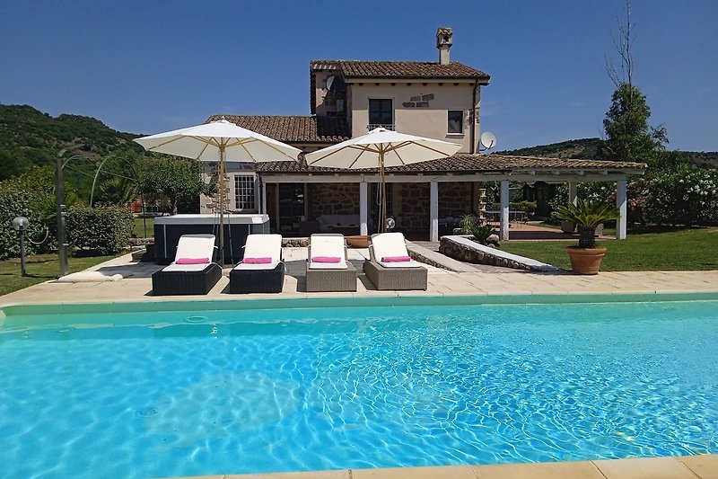 Luxuriöses Ferienhaus mit Pool, Sonnenliegen und Palmen.