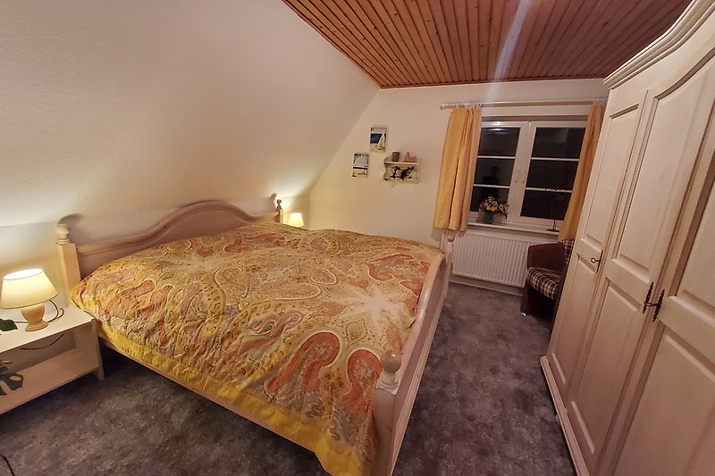 Komfortables Schlafzimmer mit stilvollem Holzmobiliar und gemütlicher Beleuchtung.