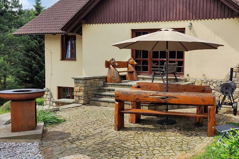 Ferienhaus mit Garten, Terrasse und Holzmöbeln in idyllischer Umgebung.