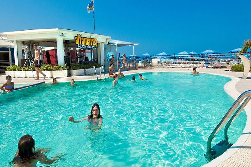 Schwimmbad mit Palmen und azurblauem Wasser. Sommerlicher Badespaß am Pool.
