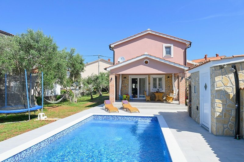 Moderne Villa mit Pool, Garten und Blick auf den blauen Himmel.