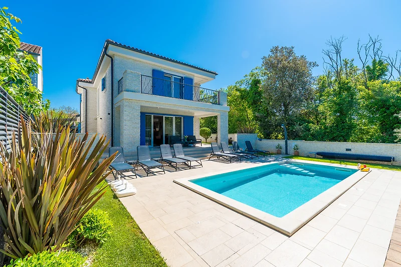 Großer Swimmingpool mit Wasseranlage, umgeben von gepflegter Gartenanlage.