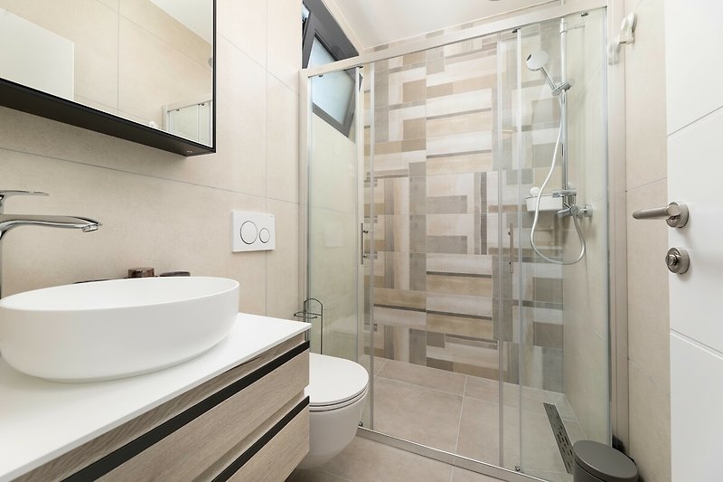 Entspannen Sie unter der modernen Dusche und genießen Sie das stilvolle Badezimmer.