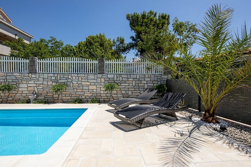 Entspannen Sie sich am Pool und genießen Sie die Sonne in dieser modernen Ferienwohnung.