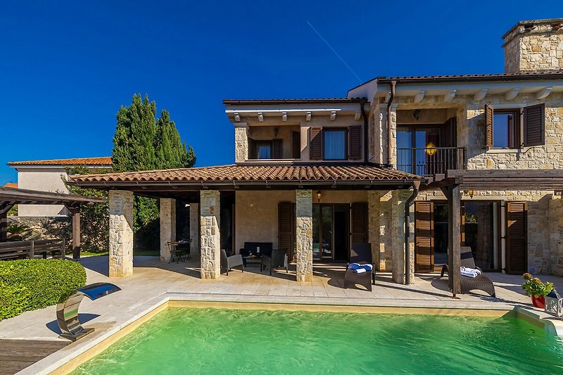 Historisches Haus mit Innenhof und Balkon, Pool im Vordergrund.