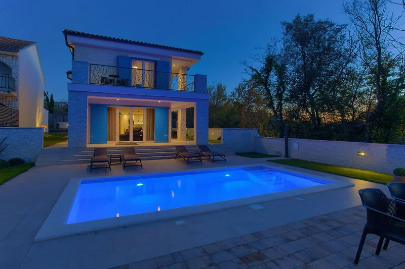 Abendstimmung am blauen Pool mit Blick auf Villen und Resortanlagen.