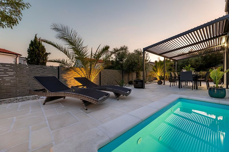 Schwimmen Sie im Pool und entspannen Sie unter dem Sonnenschirm in diesem Ferienhaus.