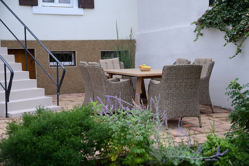 Einladende Terrasse mit Tisch, Stühlen und Pflanzen.