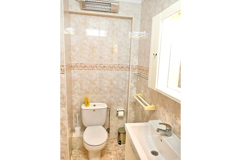 Badezimmer mit Spiegel, Toilette und Waschbecken.