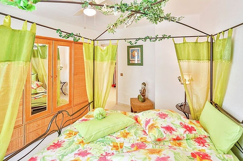 Romantisches großes Schlafzimmer mit Himmelbett und Blick in den blühenden Garten