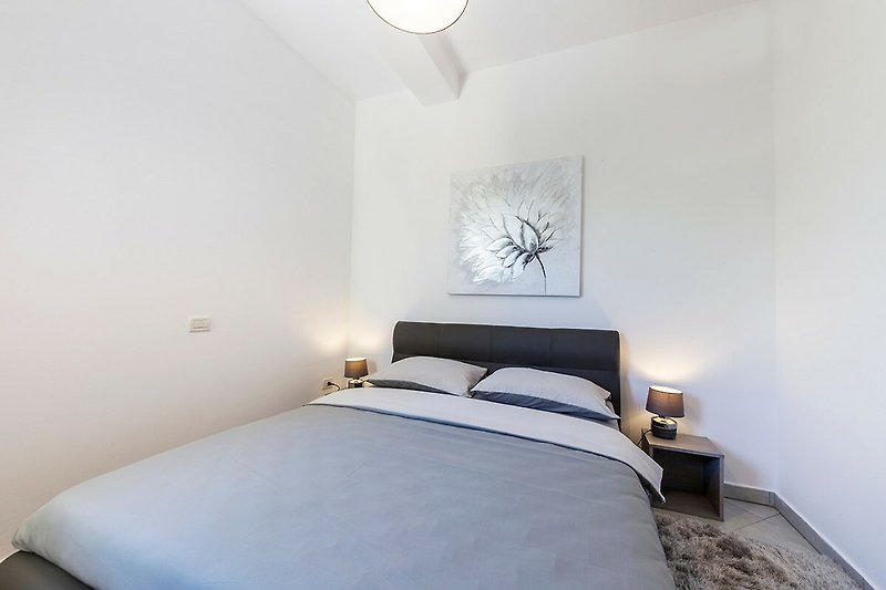 Modernes Schlafzimmer mit bequemem Bett, Lampen und Holzdetails.