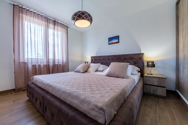 Elegantes Schlafzimmer mit Holzmöbeln, gemütlicher Beleuchtung und Bettwäsche.