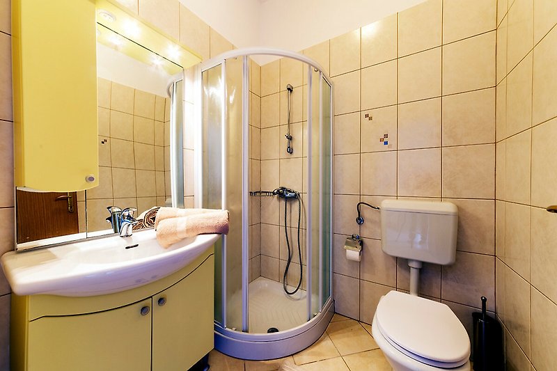 Modernes Badezimmer mit lila Akzenten, Spiegel, Waschbecken und Dusche.