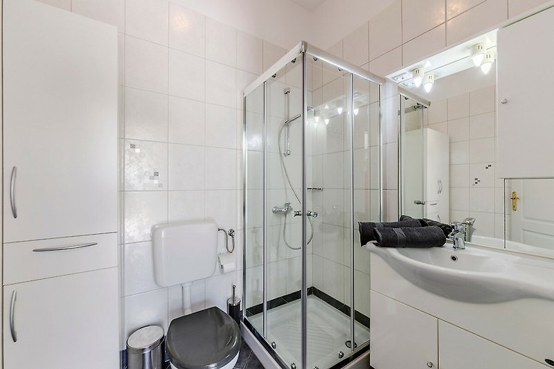 Modernes Badezimmer mit Dusche, Spiegel und Waschbecken.