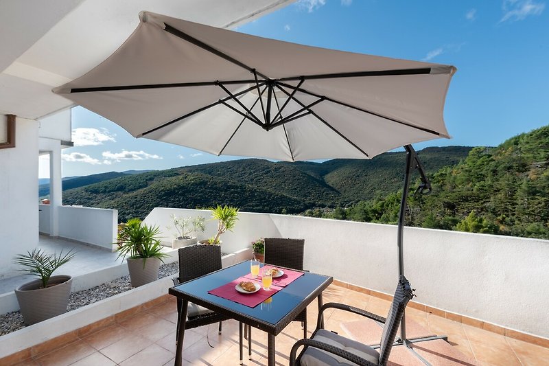 Eine entspannende Terrasse mit bequemen Möbeln und einem Sonnenschirm.