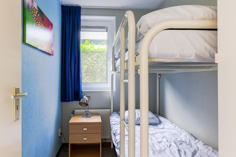 Gemütliches Schlafzimmer mit Holzbett und blauer Bettwäsche.
