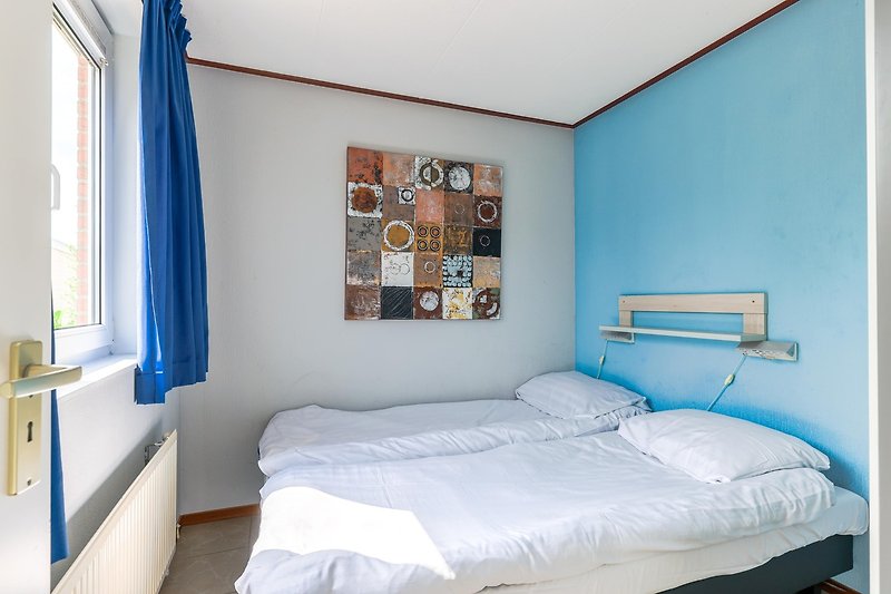 Gemütliches Schlafzimmer mit blauem Bett und Holzboden.