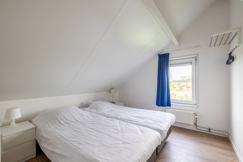 Ein komfortables Schlafzimmer mit Holzboden und gemütlichem Bett.