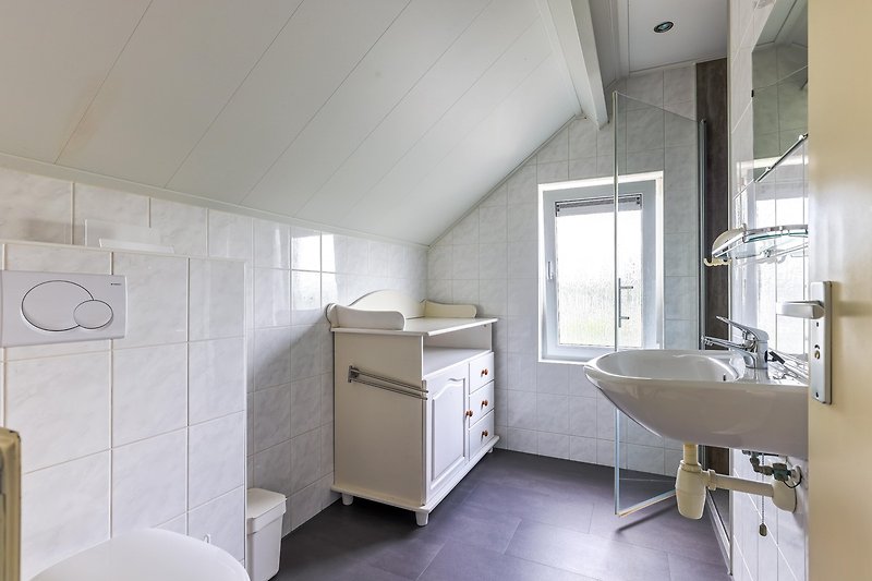 Ein modernes Badezimmer mit elegantem Spiegel und Waschbecken.