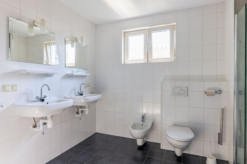 Badezimmer mit Waschbecken, Spiegel und Toilette.