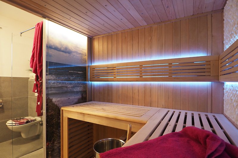Innenbereich der Sauna mit Sternenhimmel und Blick auf ein beleuchtetes Ostseebild.