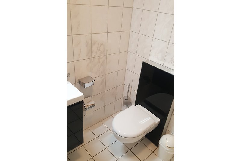 Modernes Badezimmer mit lila Toilette, schwarzer Toilettenbrille und Fliesenboden.