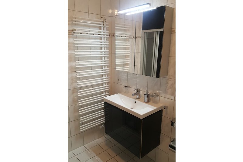 Moderne Badezimmerausstattung mit Spiegel, Wasserhahn und Waschbecken.