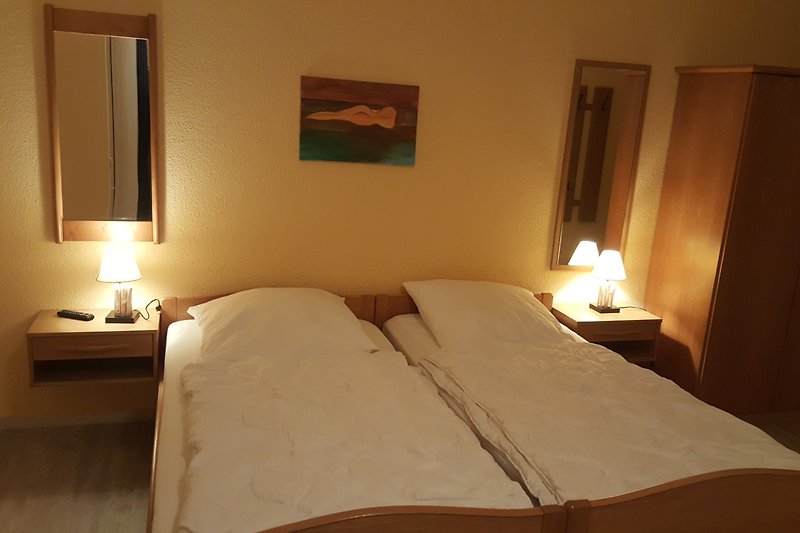 Gemütliches Schlafzimmer mit bequemem Bett, Holzmöbeln und gemütlicher Beleuchtung.