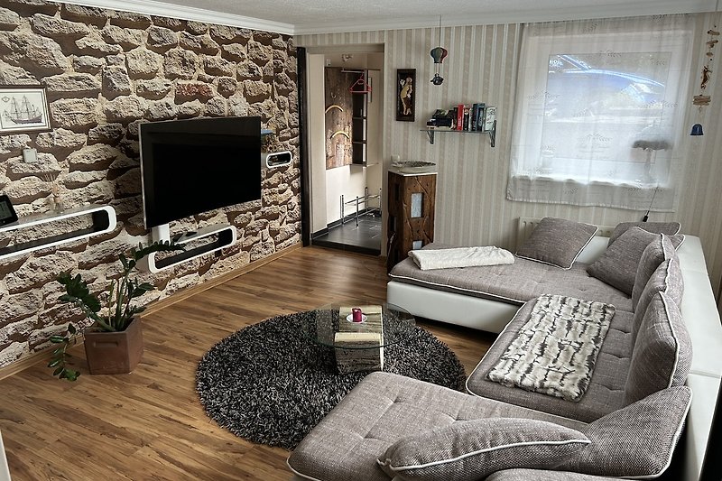 Komfortables Wohnzimmer mit großer Couch und Smart-TV.