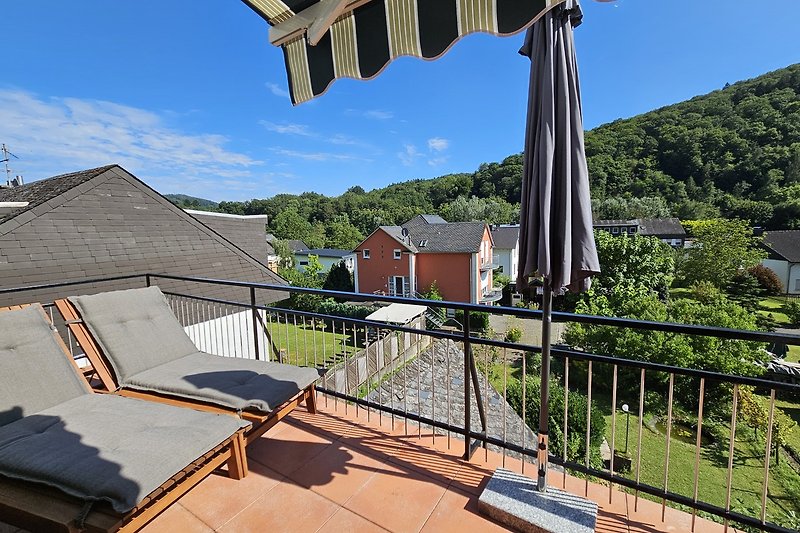 Charmantes Haus mit Balkon, Garten und blühenden Pflanzen.