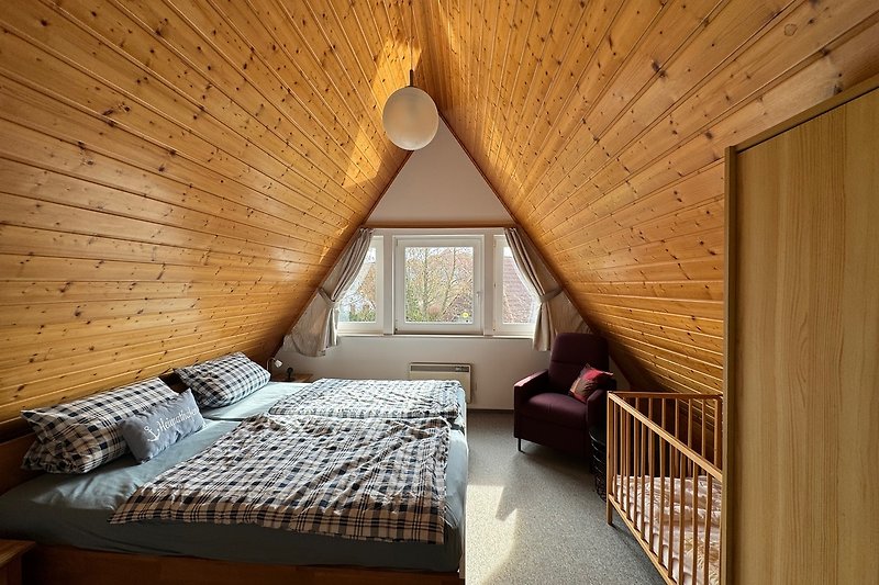 Schlafzimmer mit gemütlichem Bett, Lampe und Fenster.