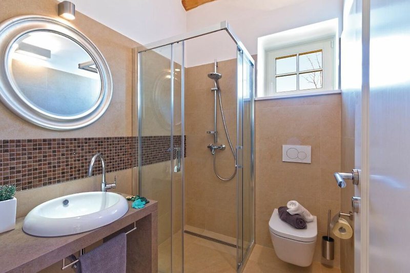 A modern bathroom with a purple sink, glass shower panel, and sleek fixtures.
